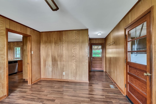 empty room with wood finished floors, healthy amount of natural light, baseboards, wood walls, and ornamental molding