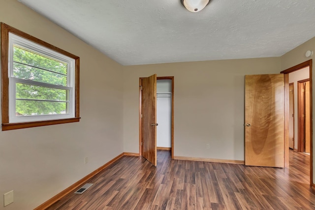 unfurnished bedroom with dark wood-style flooring, baseboards, a closet, and a textured ceiling