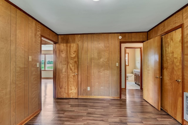 empty room with wood finished floors, ornamental molding, and wooden walls