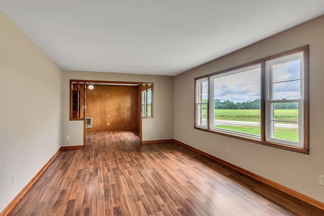 spare room with baseboards and wood finished floors