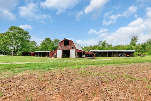 back of house with a barn, a carport, an outbuilding, and a yard