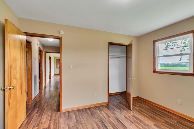 unfurnished bedroom with wood finished floors, baseboards, and a closet