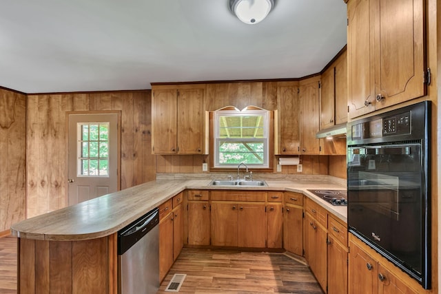 kitchen featuring a sink, black appliances, light wood-type flooring, a peninsula, and light countertops