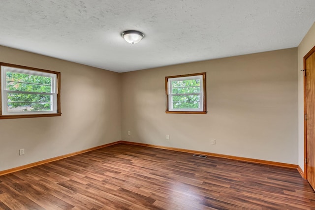 unfurnished room featuring wood finished floors, healthy amount of natural light, baseboards, and a textured ceiling