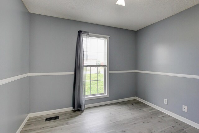 spare room featuring wood finished floors, baseboards, and a textured ceiling