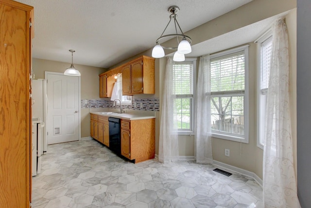 kitchen featuring a sink, light countertops, brown cabinets, decorative backsplash, and decorative light fixtures