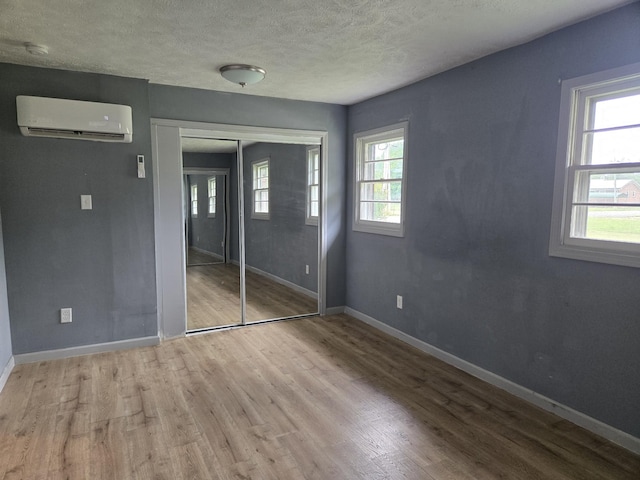307 E Commerce St, Waverly, TN 37185 - unfurnished bedroom featuring a wall mounted AC, wood finished floors, multiple windows, baseboards, and a textured ceiling