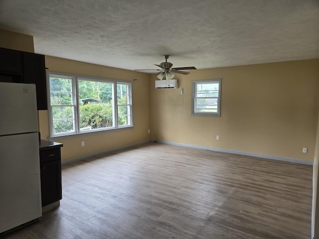 307 E Commerce St, Waverly, TN 37185 - unfurnished dining area with a textured ceiling, baseboards, wood finished floors, ceiling fan, and an AC wall unit