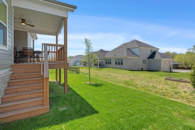 view of grassy yard featuring a ceiling fan and a wooden deck