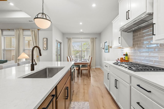 kitchen with stainless steel gas stovetop, a sink, light wood-style floors, recessed lighting, and baseboards