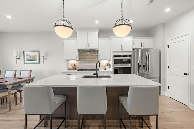 kitchen featuring stainless steel appliances, a sink, backsplash, recessed lighting, and a breakfast bar area