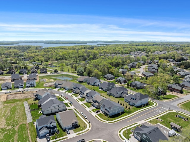 aerial perspective of suburban area featuring a nearby body of water and a forest