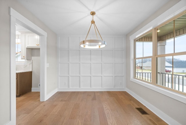 1912 Flats Rd, Cunningham, TN 37052 - unfurnished dining area featuring light wood-style floors, a decorative wall, baseboards, and a chandelier