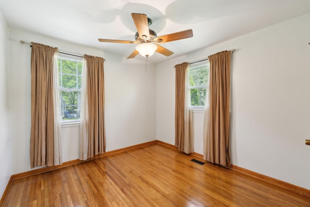 unfurnished room featuring plenty of natural light, light wood finished floors, ceiling fan, and baseboards
