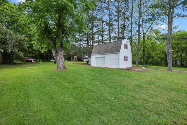 view of green lawn featuring an outdoor structure and a detached garage
