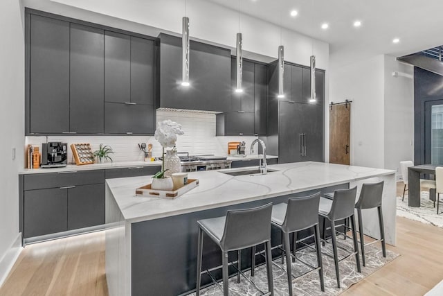 4303A Utah Ave, Nashville, TN 37209 - kitchen with a sink, modern cabinets, light wood finished floors, a kitchen island with sink, and tasteful backsplash