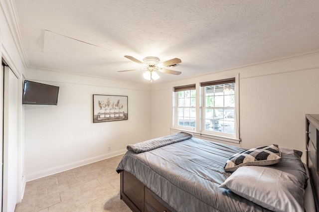 bedroom featuring ornamental molding, baseboards, a ceiling fan, and a textured ceiling