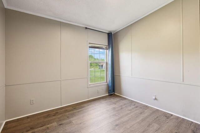 empty room featuring wood finished floors, crown molding, and a textured ceiling