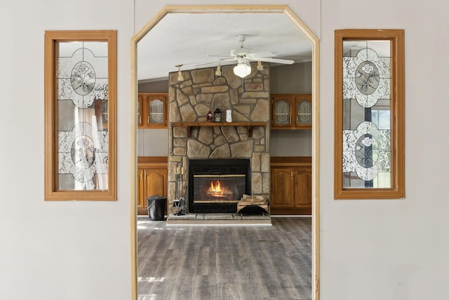 unfurnished living room featuring ceiling fan, a fireplace, and wood finished floors
