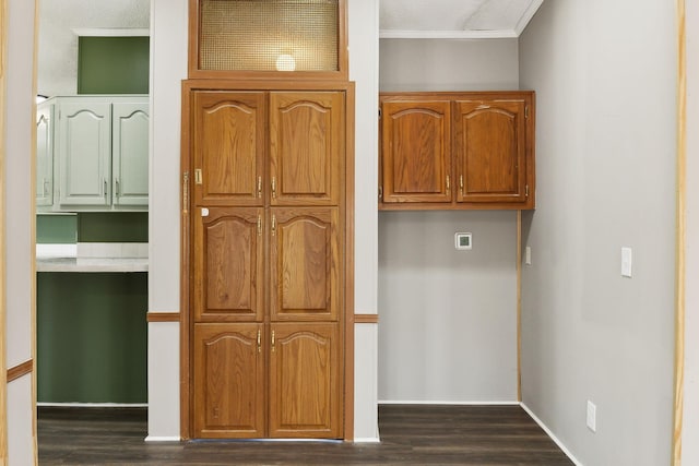 kitchen featuring dark wood-type flooring, brown cabinets, baseboards, and ornamental molding