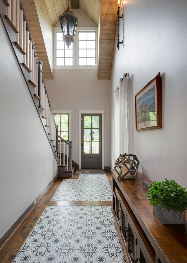 foyer entrance featuring plenty of natural light, a chandelier, stairway, high vaulted ceiling, and wood finished floors