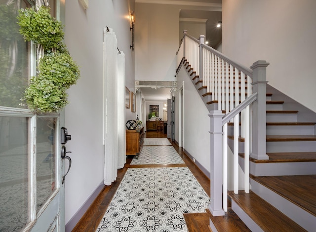 foyer with dark wood-style floors, stairs, a towering ceiling, and baseboards