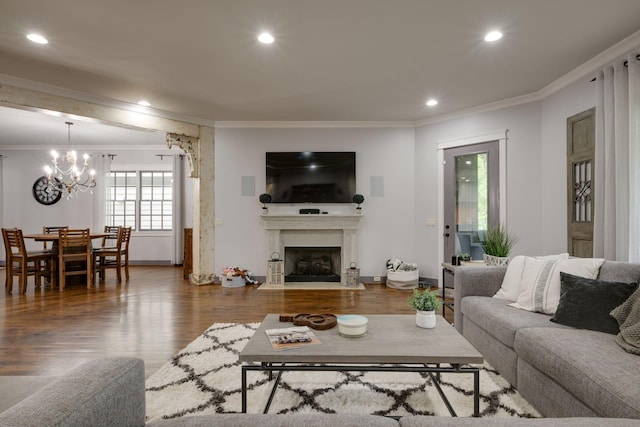 living area featuring ornamental molding, a chandelier, wood finished floors, a fireplace with flush hearth, and recessed lighting