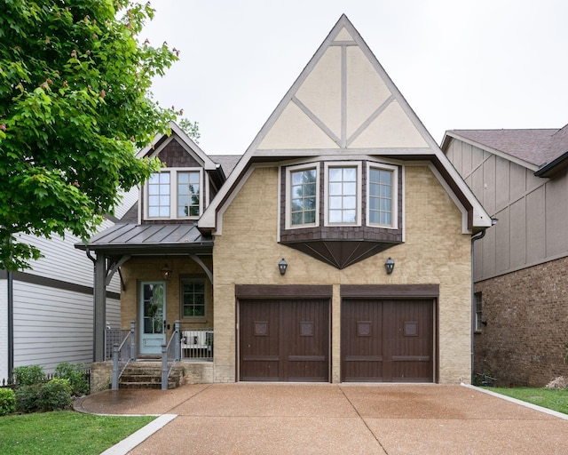 view of front of house featuring a garage, a standing seam roof, covered porch, driveway, and stucco siding