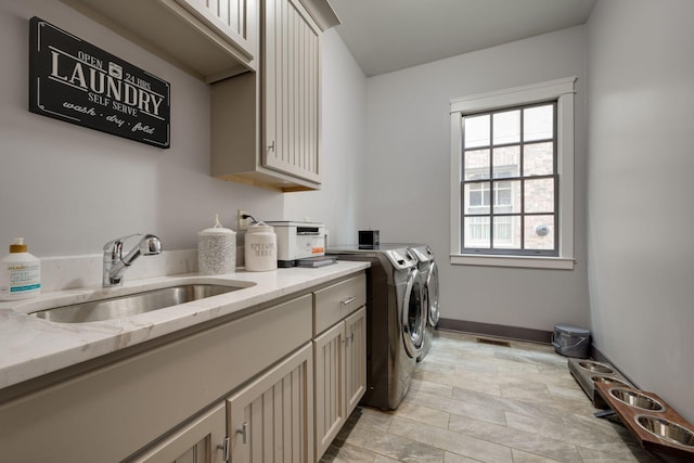 laundry room featuring cabinet space, washing machine and clothes dryer, baseboards, and light stone finish floors