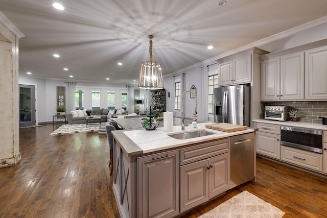kitchen featuring a sink, appliances with stainless steel finishes, crown molding, an island with sink, and recessed lighting