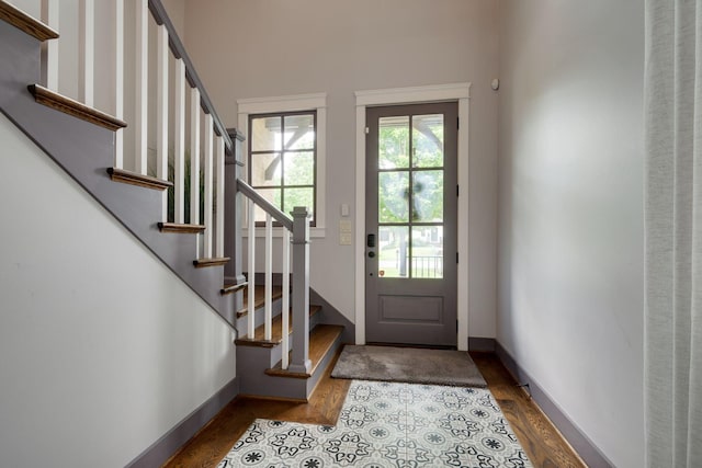 doorway to outside featuring dark wood-type flooring, stairway, and baseboards