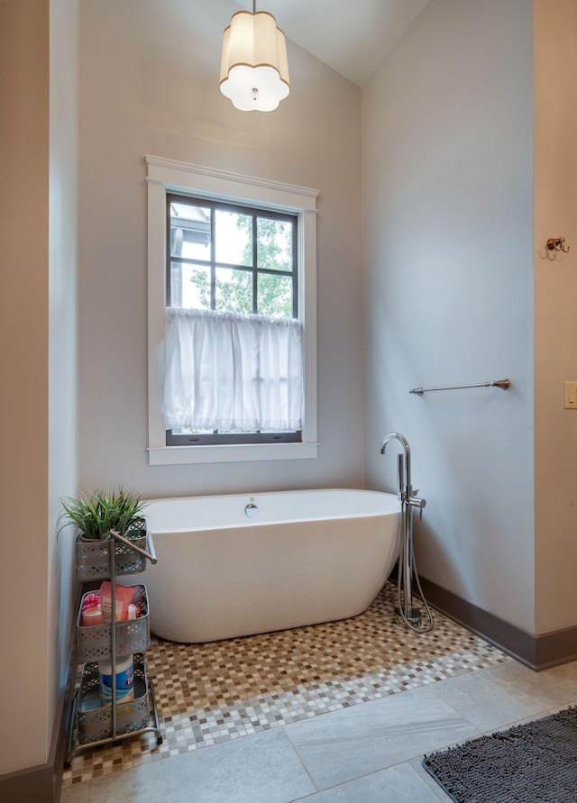 bathroom with a soaking tub, lofted ceiling, and baseboards