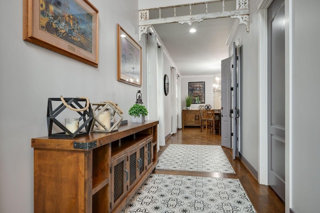 hallway with ornamental molding, dark wood-type flooring, and baseboards