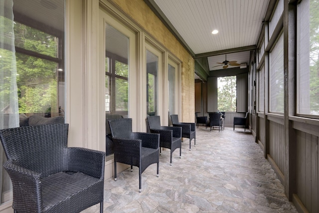 sunroom / solarium with stone finish floors and a ceiling fan