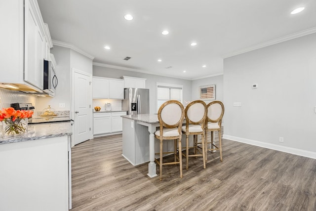 1006 Brinxton Run, Murfreesboro, TN 37128 - kitchen with appliances with stainless steel finishes, ornamental molding, light wood-type flooring, an island with sink, and white cabinets