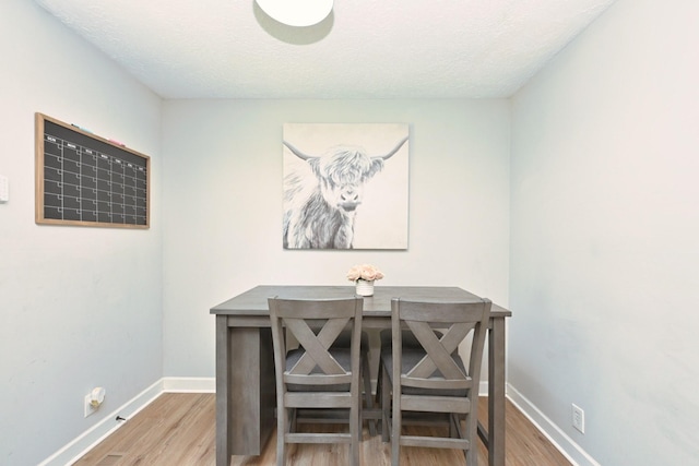 dining area with wood finished floors, baseboards, and a textured ceiling