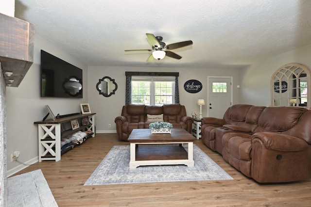 living room with a ceiling fan, a textured ceiling, baseboards, and wood finished floors