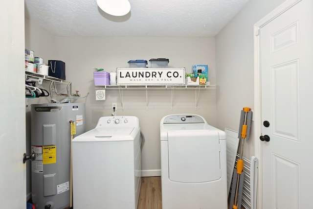 laundry area featuring water heater, washing machine and dryer, wood finished floors, and a textured ceiling
