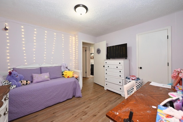 bedroom with light wood finished floors and a textured ceiling