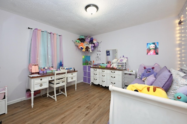 bedroom with wood finished floors, a textured ceiling, and baseboards