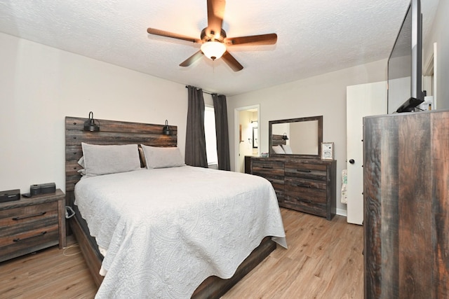 bedroom with light wood-style flooring, a textured ceiling, and a ceiling fan