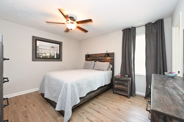 bedroom with light wood finished floors, baseboards, and ceiling fan
