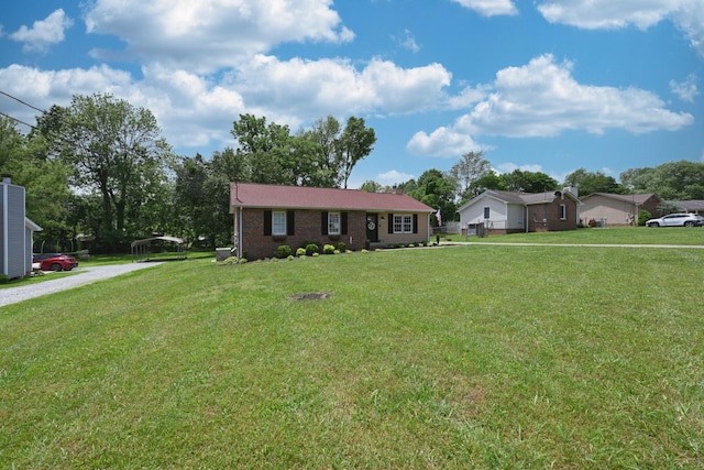 ranch-style home featuring a front lawn, gravel driveway, and brick siding