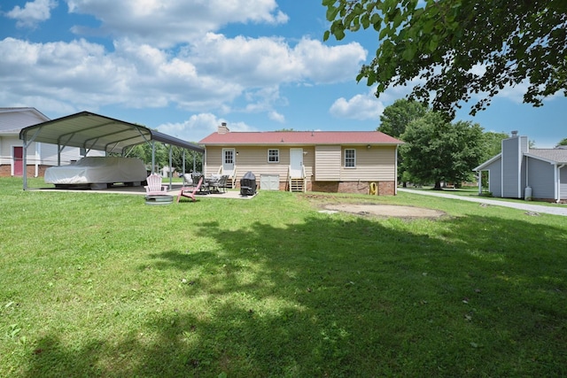rear view of property featuring entry steps, a yard, a detached carport, and a chimney