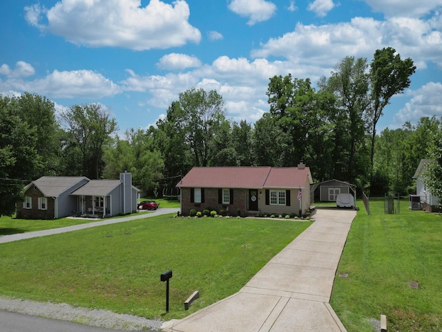 ranch-style house featuring concrete driveway, a front yard, a carport, a storage unit, and an outdoor structure