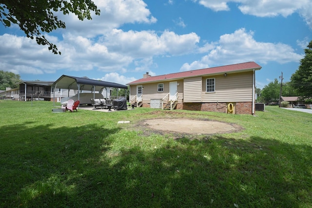 back of property featuring entry steps, central air condition unit, a yard, and a carport