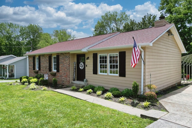 ranch-style home with a front yard, a chimney, roof with shingles, and brick siding