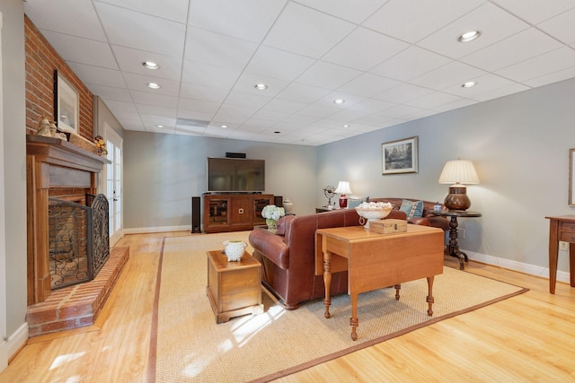 living area with wood finished floors, a fireplace, baseboards, a drop ceiling, and recessed lighting
