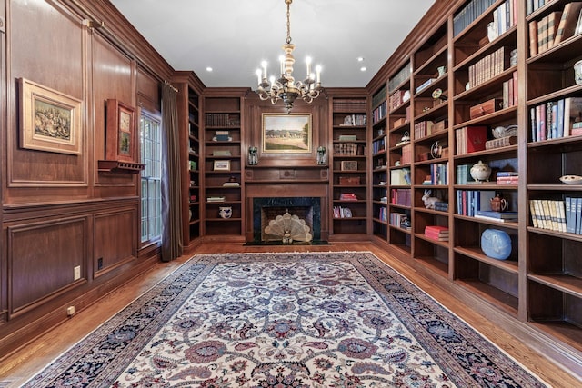 sitting room featuring a chandelier, wood finished floors, built in features, a fireplace, and ornamental molding