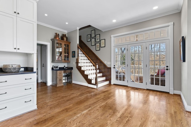 doorway to outside with ornamental molding, light wood finished floors, baseboards, stairs, and recessed lighting